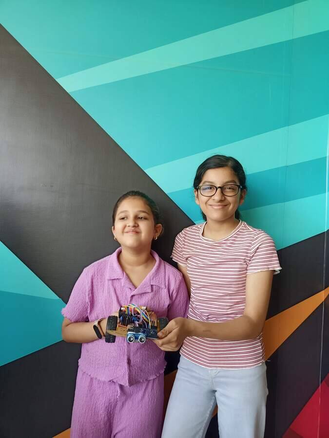 Two students holding Arduino robot cars they assembled during a STEMForge robotics session