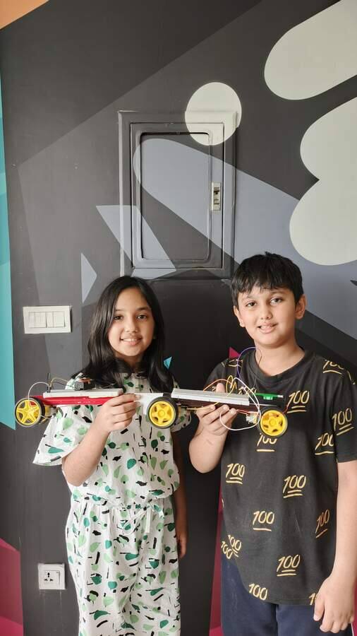 Two young students showing the robot chassis they built together in a STEMForge workshop