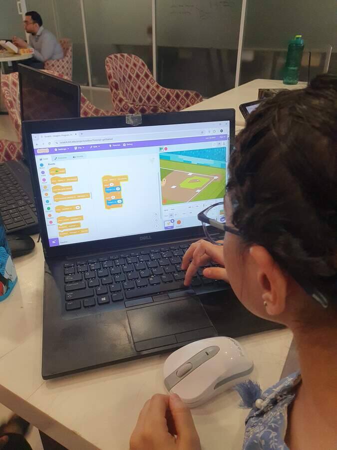 Student writing her first program on a laptop during a STEMForge coding workshop
